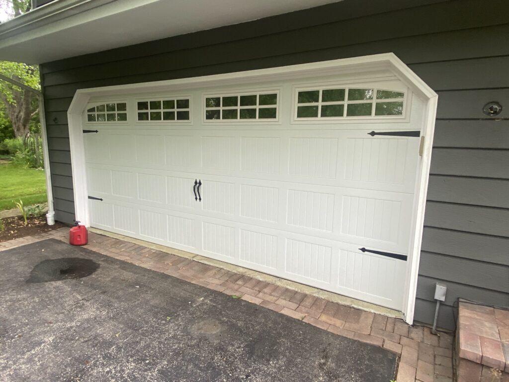 White carriage garage door with windows and black handles and hinges 